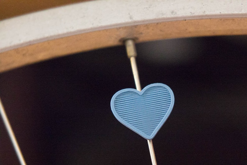 Pu&ograve; includere: Un ciondolo a forma di cuore blu appeso a un raggio di una ruota di bicicletta.