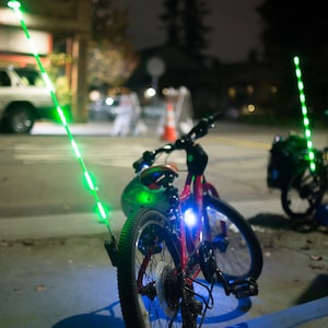 Two bicycles, parked, with light up LED glow sticks attached.