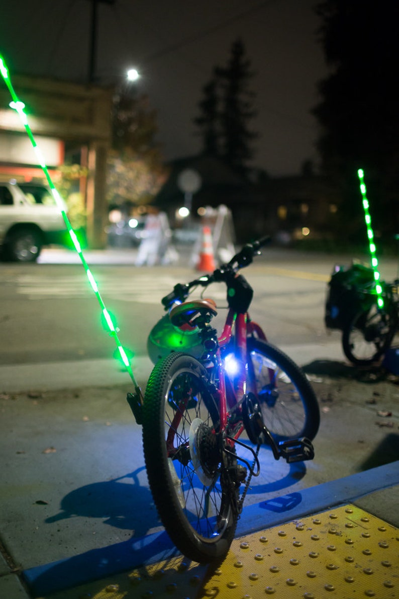 Two bicycles, parked, with light up LED glow sticks attached.