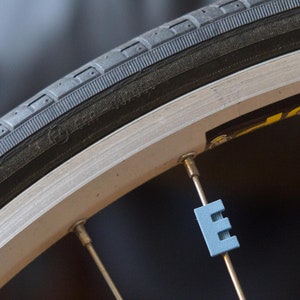 Letter &quot;E&quot; Bike Spoke Decoration. Fits on bicycle wheel spokes. This accessory clips onto bike spokes like spoke beads. Made in USA.