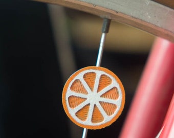 Orange slice spoke decoration. Fits bike wheels, wheelchairs. Accessory clips on like spoke beads, charms. Mount in center or near tires.