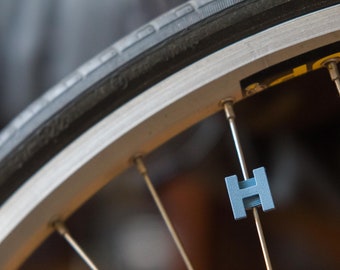 Letter "H" Bike Spoke Decoration. Fits on bicycle wheel spokes. Accessory clips onto bike spokes like spoke beads. Made in USA.
