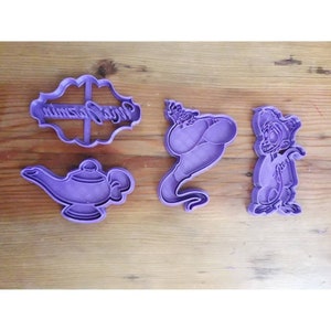 Pode incluir: Conjunto de quatro cortadores de biscoitos de plástico roxo com personagens e texto do filme Aladdin. Os cortadores incluem um gênio, Abu, uma lâmpada e uma placa que diz "Wish Jasmine".