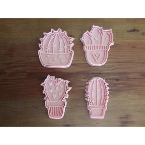 Può includere: Set di quattro tagliapasta a forma di cactus in plastica rosa. I tagliapasta hanno la forma di cactus diversi con vari dettagli, tra cui cuori, punti ed spine.