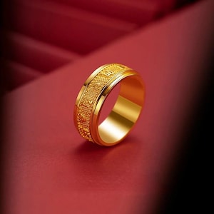 Puede incluir: Un anillo de color dorado con diseños intrincados y un acabado liso y pulido.