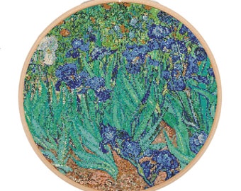 Puede incluir: Un primer plano de un bordado de punto de cruz de una pintura de iris azules con hojas verdes. El bordado está enmarcado en un aro de madera redondo.
