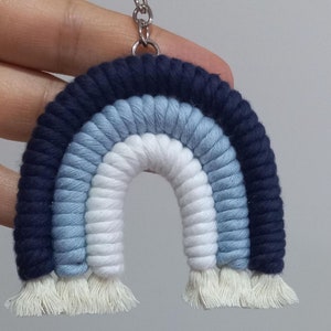 Könnte beinhalten: Ein blauer, weißer und hellblauer Regenbogen-Schlüsselanhänger aus Garn mit einer silbernen Kette.