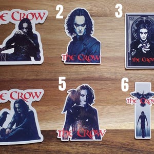 May include: Six different stickers featuring the movie The Crow. Each sticker features a different image of the main character, Eric Draven, and the title of the movie. The stickers are printed on white paper with a glossy finish.