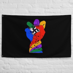 Puede incluir: Una bandera negra con un gesto de la mano colorido que forma un signo de la paz. La mano está pintada en varios colores, incluyendo azul, verde, morado, amarillo y rojo, con un diseño en blanco y negro en el centro.