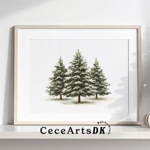 May include: A framed print featuring three evergreen trees with snow-covered branches. A small Christmas tree with ornaments and a decorative pumpkin sit on a white shelf. The text "CeceArtsDK" is visible on the frame.