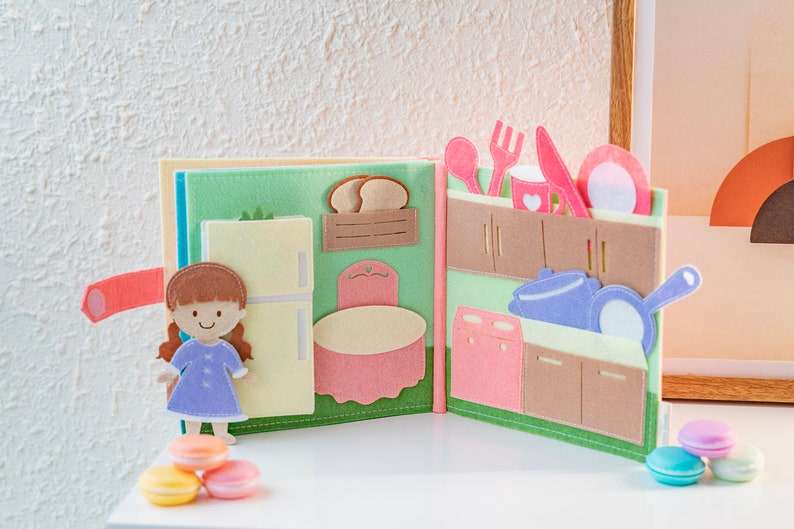 page 5 and page 6 of dollhouse quiet book, square shaped, felt material, light and soft, simulates kitchen room, with refrigerator white color is close, 1 dining table pastel pink, kitchen tools on pastel pink and violet
