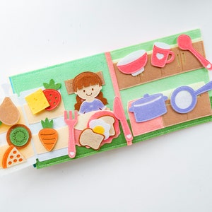 dollhouse quiet book page 5 and 6 square shaped, felt material, light and soft, about baby breakfast with a lot food on table and refrigerator is open with full of full as potato, kiwi, cheese, carrot, strawberry. pastel color