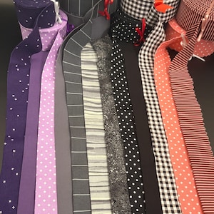 May include: A collection of fabric ribbons in various patterns and colors, including purple with white geometric shapes, light purple with white polka dots, grey with white stripes, black with white polka dots, black and white gingham, and coral.