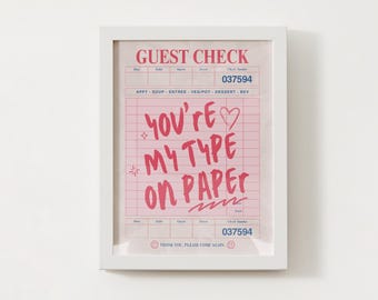 Puede incluir: Impresión enmarcada con un diseño de recibo rosa. El texto "YOU'RE MY TYPE ON PAPER" es rojo. La impresión incluye el número de cheque 037594 y una carita sonriente. Una pieza decorativa para el hogar.
