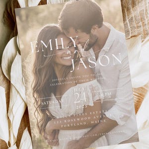 Puede incluir: Una invitación de boda con una foto de una pareja abrazándose. La invitación es blanca con un fondo marrón claro y presenta los nombres "Emily y Jason" en una fuente de letra cursiva. El texto dice "Joyfully invite you to the celebration of their wedding" e incluye la fecha "Saturday, July 24, 2025, 6 PM". La ubicación se indica como "Molea Pines Estate, 123 Rosewood Avenue, Portland, Maine".