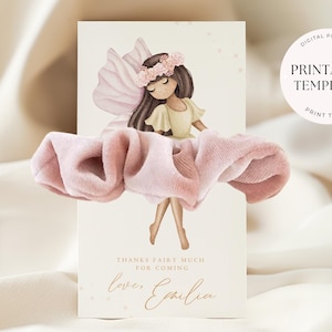 Könnte beinhalten: Eine Grußkarte mit einer Feenillustration, rosa Flügeln und einem Blumenkranz. Auf der Karte steht "THANKS FAIRY MUCH FOR COMING" und "love, Emilia". Vor der Karte liegt ein rosa Haargummi. Die Worte "DIGITALES PRODUKT" und "DRUCKBARE VORLAGE" sind ebenfalls sichtbar.