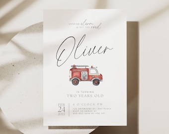 May include: A red fire truck with a white ladder and black wheels is on a white card with the text "Oliver is turning two years old" and "Feb 24, 2022" in black text.