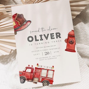 K&ouml;nnte beinhalten: Ein rotes und wei&szlig;es Feuerwehrauto mit einer Leiter und einem Feuerwehrhelm oben drauf. Das Auto steht auf einem wei&szlig;en Hintergrund mit dem Text "sound the alarm OLIVER IS TURNING THREE Let's fire up some fun for OLIVER'S FIRST BIRTHDAY SEPT 20 2PM 123 ANYWHERE ST. ANY CITY RSVP TO SAMANTHA our dearest MOMENTS DESIGN CO."