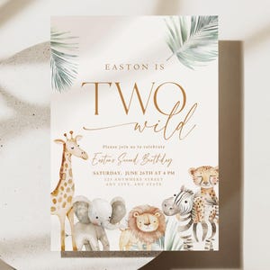 Op de afbeelding: Een lichtbruine uitnodigingskaart met een jungle-thema. De kaart heeft de tekst "Easton is Two Wild" in gouden letters. De kaart is versierd met aquarel-illustraties van een giraffe, een olifant, een leeuw en een zebra. De tekst op de kaart luidt: "Nodig je uit om Eastons tweede verjaardag te vieren, zaterdag 26 juni om 16:00 uur, 11 Anywhere Street, Any City, Any State."