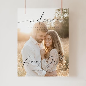 Könnte beinhalten: Ein rechteckiges Willkommensschild für eine Verlobungsfeier mit einem Foto eines Paares, das sich auf einem Feld umarmt. Der Text lautet "welcome TO THE ENGAGEMENT PARTY OF Avery + Josh SEPTEMBER 5TH, 20XX" in schwarzer Schreib- und Druckschrift.