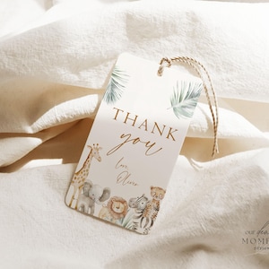 May include: A thank you tag with a watercolor illustration of a giraffe, elephant, lion, and zebra. The tag is decorated with green leaves and has the text "Thank you" in gold lettering. The text "Love, Oliver" is written below the thank you message.