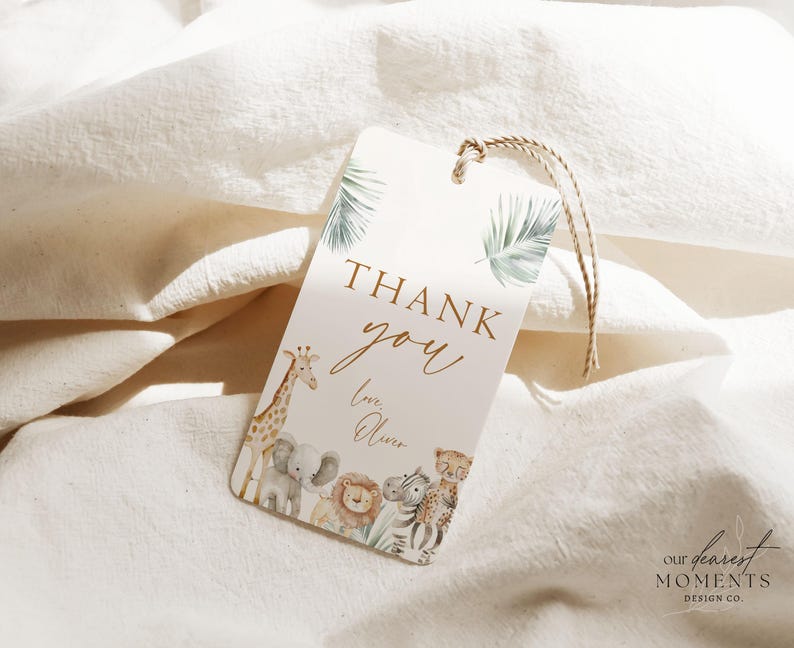May include: A thank you tag with a watercolor illustration of a giraffe, elephant, lion, and zebra. The tag is decorated with green leaves and has the text "Thank you" in gold lettering. The text "Love, Oliver" is written below the thank you message.