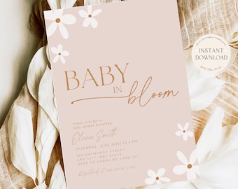 May include: A pink baby shower invitation with white flowers and gold text. The text reads "Baby in Bloom" and includes the name Olivia Smith, the date and time of the shower, and the address. The invitation also includes the text "RSVP to Sarah by June 1st" and "Registered at Amazon.com".