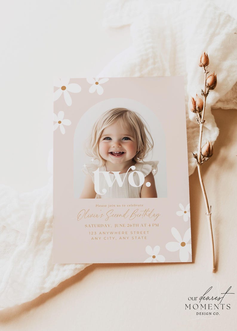 May include: A pink and white birthday invitation with a photo of a young child. The invitation says "Please join us to celebrate Olivia's Second Birthday" and includes the date, time, and location of the party. The invitation is decorated with white daisies with gold centers.