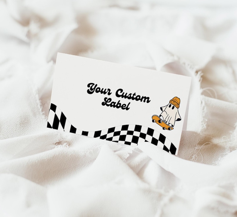 May include: White card with black and white checkered border and a ghost wearing a yellow beanie riding a skateboard. The text "Your Custom Label" is written in a retro font.
