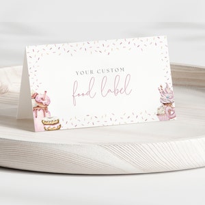 May include: A white card with a pink border and pink sprinkles. The card says "Your Custom Food Label" in pink script. There are illustrations of donuts, cupcakes, and milkshakes on the card.