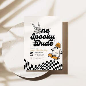 May include: A white invitation card with black and orange text that reads "One Spooky Dude", a ghost wearing a beanie riding a skateboard, and a black and white checkered pattern. The text also includes "Join us for [Name]'s First Birthday", "Saturday, October 31st", and "4 o'clock pm".