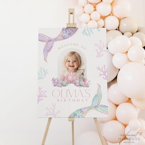 May include: A welcome sign for a birthday party with a mermaid tail, seashells, and coral. The sign says "Welcome to Olivia's Birthday".