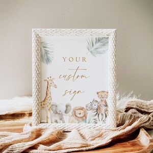 May include: A white frame with a white mat and a gold inscription that reads "YOUR custom sign". The frame features a watercolor illustration of a giraffe, elephant, lion, zebra, and leopard against a green palm leaf background.