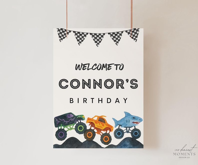 May include: A white poster with the text "Welcome to Connor's Birthday" and three monster truck illustrations. The trucks are purple, orange, and blue, with black and white checkered flags at the top.