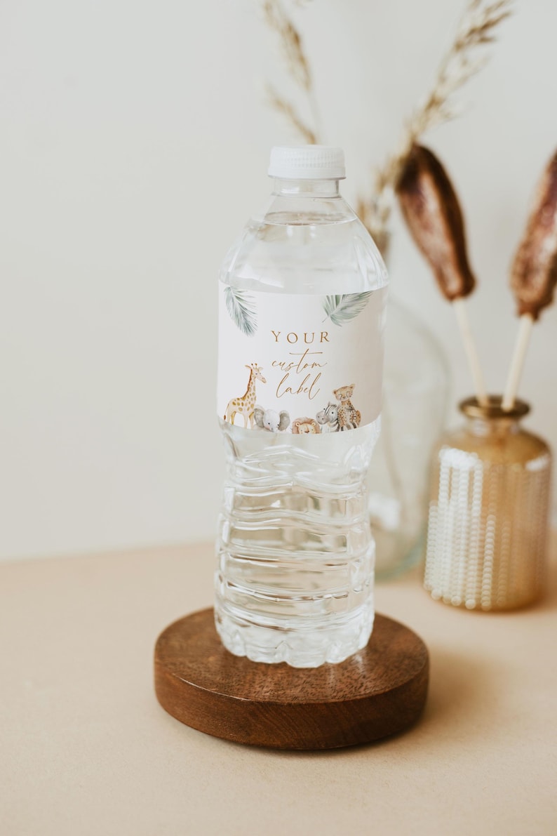 May include: A clear plastic water bottle with a white cap and a label that says "YOUR custom label". The label features a watercolor illustration of a giraffe, a cheetah, an elephant, a monkey, and a zebra. The bottle is sitting on a wooden coaster.