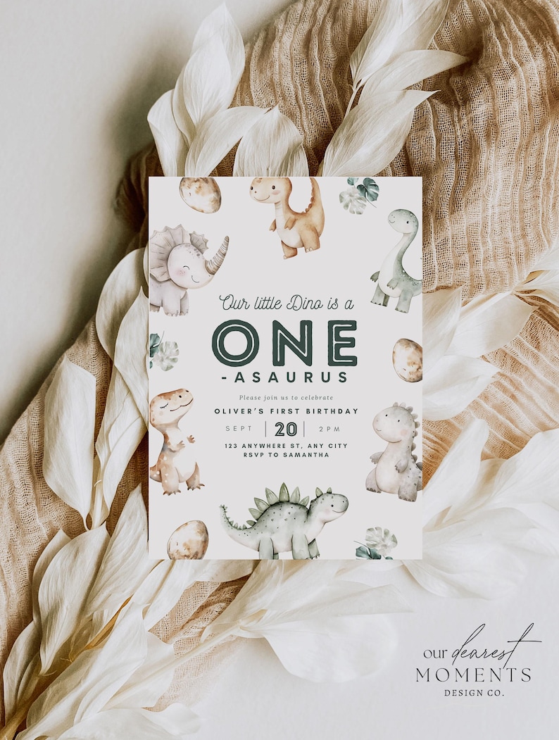 May include: A white invitation card with a green and brown dinosaur illustration. The text reads "Our little Dino is a ONE -ASAURUS. Please join us to celebrate OLIVER'S FIRST BIRTHDAY. SEPT | 20 | 2PM. 123 ANYWHERE ST, ANY CITY. RSVP TO SAMANTHA. our dearest MOMENTS DESIGN CO."