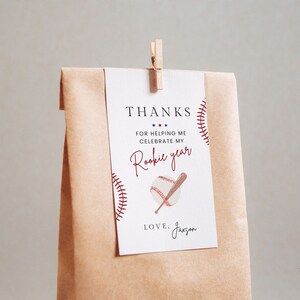 May include: A white thank you card with red and blue accents. The card features a baseball and bat graphic and the text "THANKS FOR HELPING ME CELEBRATE MY Rookie year LOVE. Jaxsan".