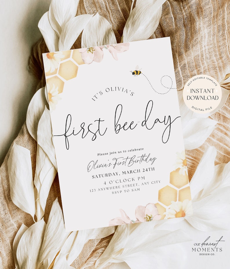 May include: A printable invitation for a first birthday party with a bee theme. The invitation features a watercolour illustration of a honeycomb, flowers, and a bee. The text reads "It's Olivia's First Bee Day" and includes details about the party, such as the date, time, and location. The invitation also includes the text "Our Dearest Moments Design Co."
