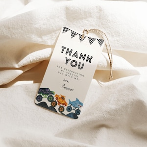 May include: A white gift tag with the words "THANK YOU" in bold black letters. Below the text are the words "FOR CELEBRATING MY SPECIAL DAY WITH ME! Love, Conner." The bottom of the tag features illustrations of monster trucks. A string is attached to the top.