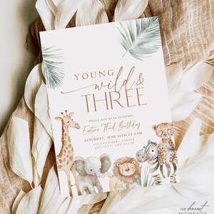 May include: A white invitation card with a jungle theme. The text reads "Young Wild & Three" with a brown giraffe, elephant, lion, and zebra illustration. The invitation is for Easton's Third Birthday party.