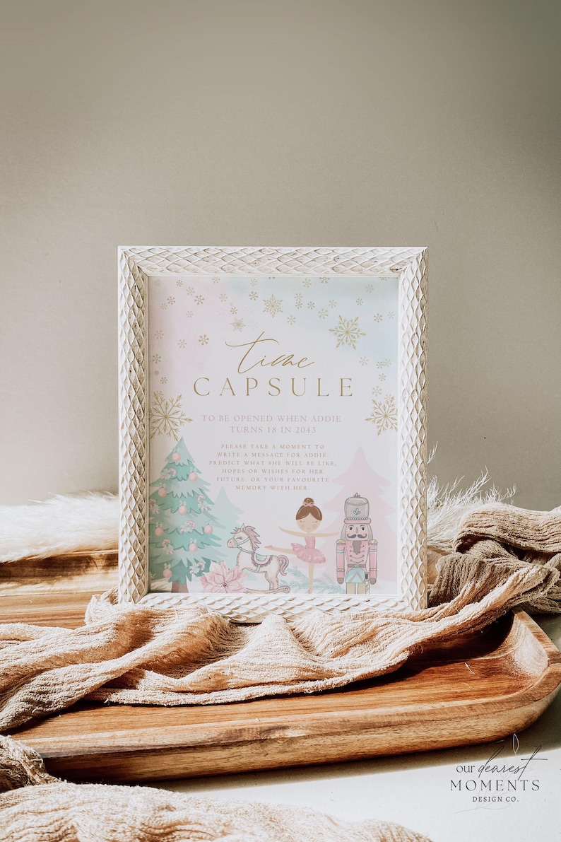 May include: A framed print with the words "Time Capsule" and decorative snowflakes. The print features a Christmas tree, a ballerina, a toy horse, and a nutcracker. The text reads "To be opened when Addie turns 18 in 2043."