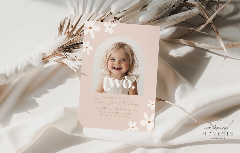 May include: A pink birthday invitation with white flowers and the word "two" in a white circle. A photo of a young girl is in the circle. The text reads "Please join us in celebrating [Name]'s Second Birthday. [Date] at [Time]. [Address]. [City, State]".