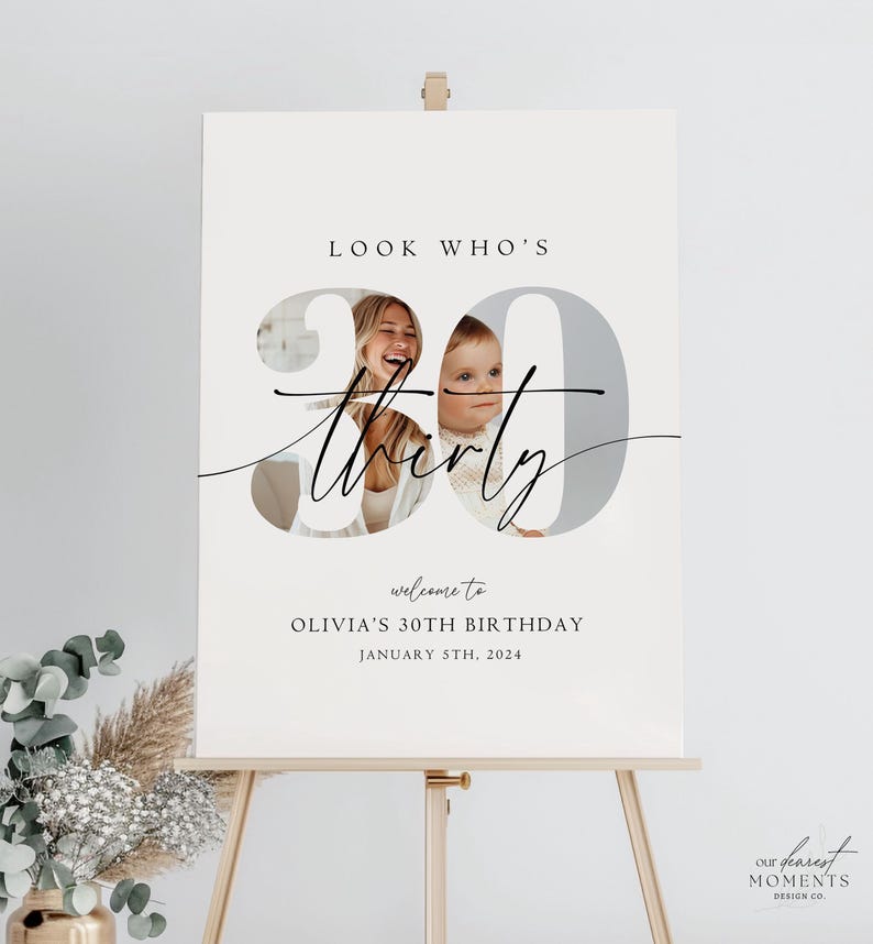 Op de afbeelding: Een wit welkomsbord met een foto van een vrouw en een kind in het getal 30. De tekst luidt "Look Who's Thirty" en "Welcome to Olivia's 30th Birthday January 5th, 2024".