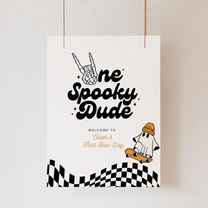 May include: A white sign with black text that reads "One Spooky Dude" and "Welcome to Oliver's First Boo-Day". A cartoon ghost wearing a beanie is skateboarding over a black and white checkered pattern.