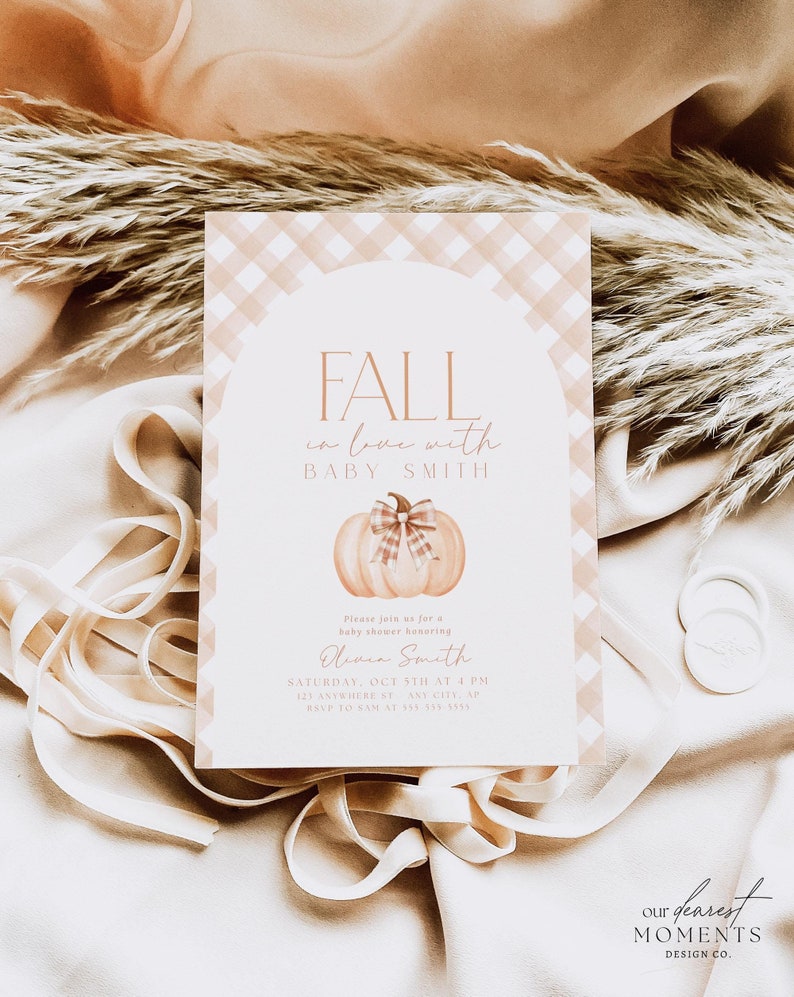 Pode incluir: Um convite para um ch&aacute; de beb&ecirc; com tema de outono. O convite apresenta uma ilustra&ccedil;&atilde;o em aquarela de uma ab&oacute;bora com um la&ccedil;o xadrez rosa e branco. O texto do convite diz "Fall in love with Baby Smith".
