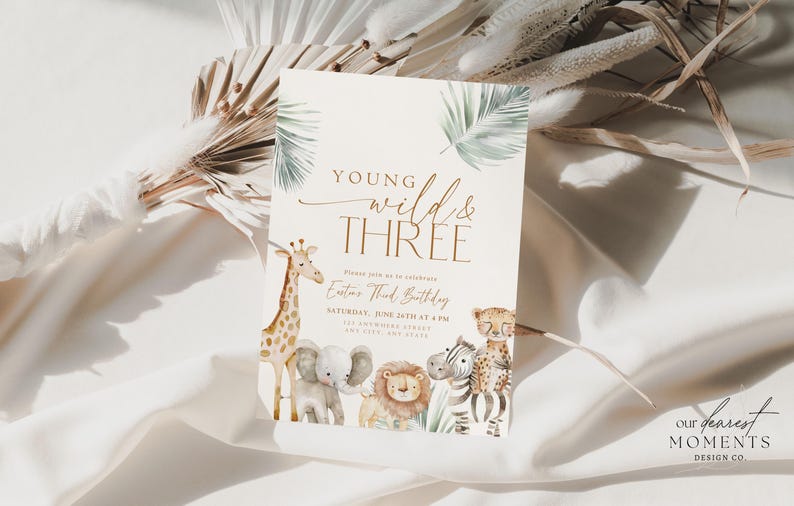 May include: A white invitation card with a jungle theme. The card features a giraffe, elephant, lion, and zebra with the text "Young Wild & Three" and "Enter Third Birthday" in gold lettering.
