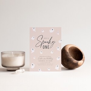 May include: A pink and white Halloween-themed invitation with the text "He's a Spooky One" and a ghost pattern. The invitation is for a first birthday party.