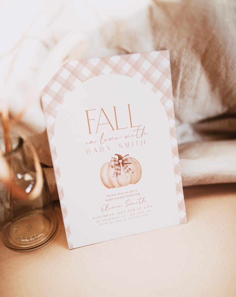 Pode incluir: Um convite para um ch&aacute; de beb&ecirc; em gingham rosa e branco com uma ilustra&ccedil;&atilde;o em aquarela de uma ab&oacute;bora com um la&ccedil;o. O texto diz "Fall in love with Baby Smith" e inclui a data e hora do ch&aacute; de beb&ecirc;.