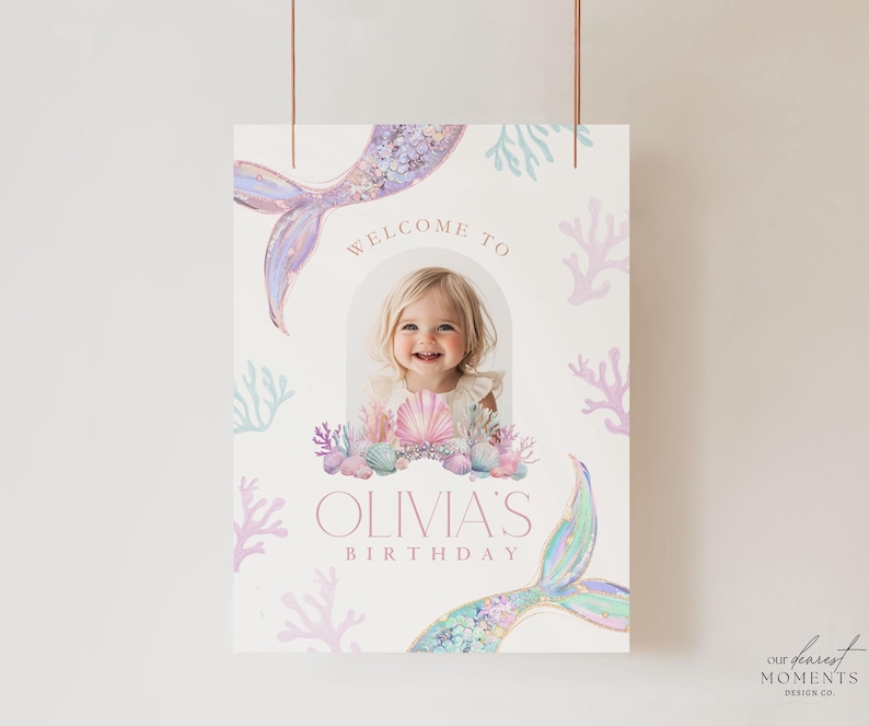 May include: A welcome sign for a birthday party with a mermaid tail, seashells, and coral. The sign says "Welcome to Olivia's Birthday".