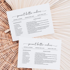 May include: Two printable recipe cards for peanut butter cookies. The cards are white with black text and include the ingredients and directions for making the cookies. The cards are on a woven wicker background.